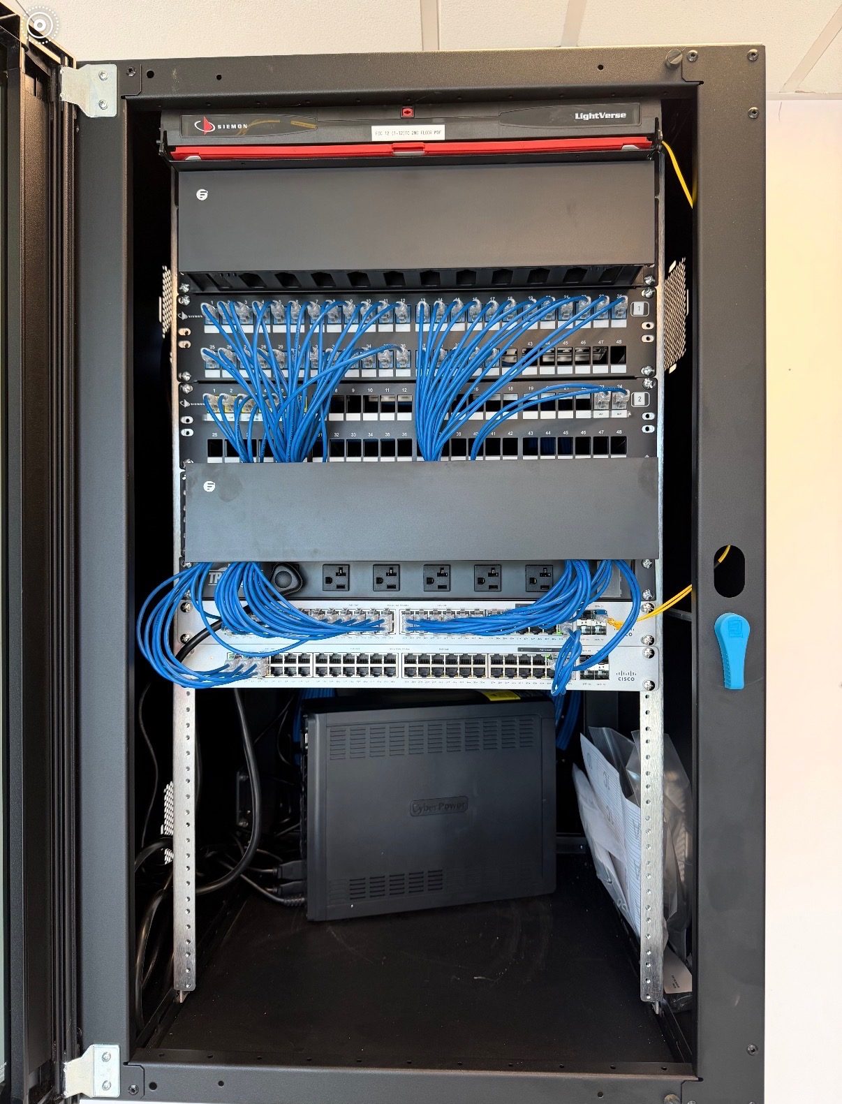 Network rack with blue patch cables neatly routed to switches and patch panels