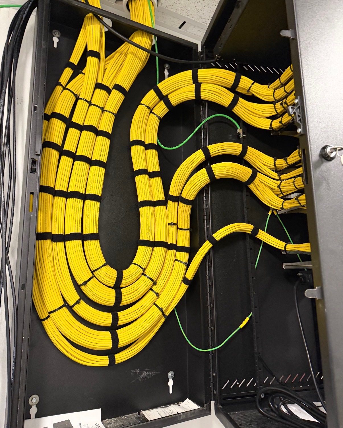 Bundles of yellow fiber cable looped inside an enclosure with the bend radius protected