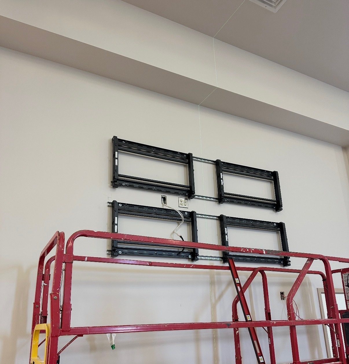 Four TV wall mounts set and leveled on a wall with a lift in front